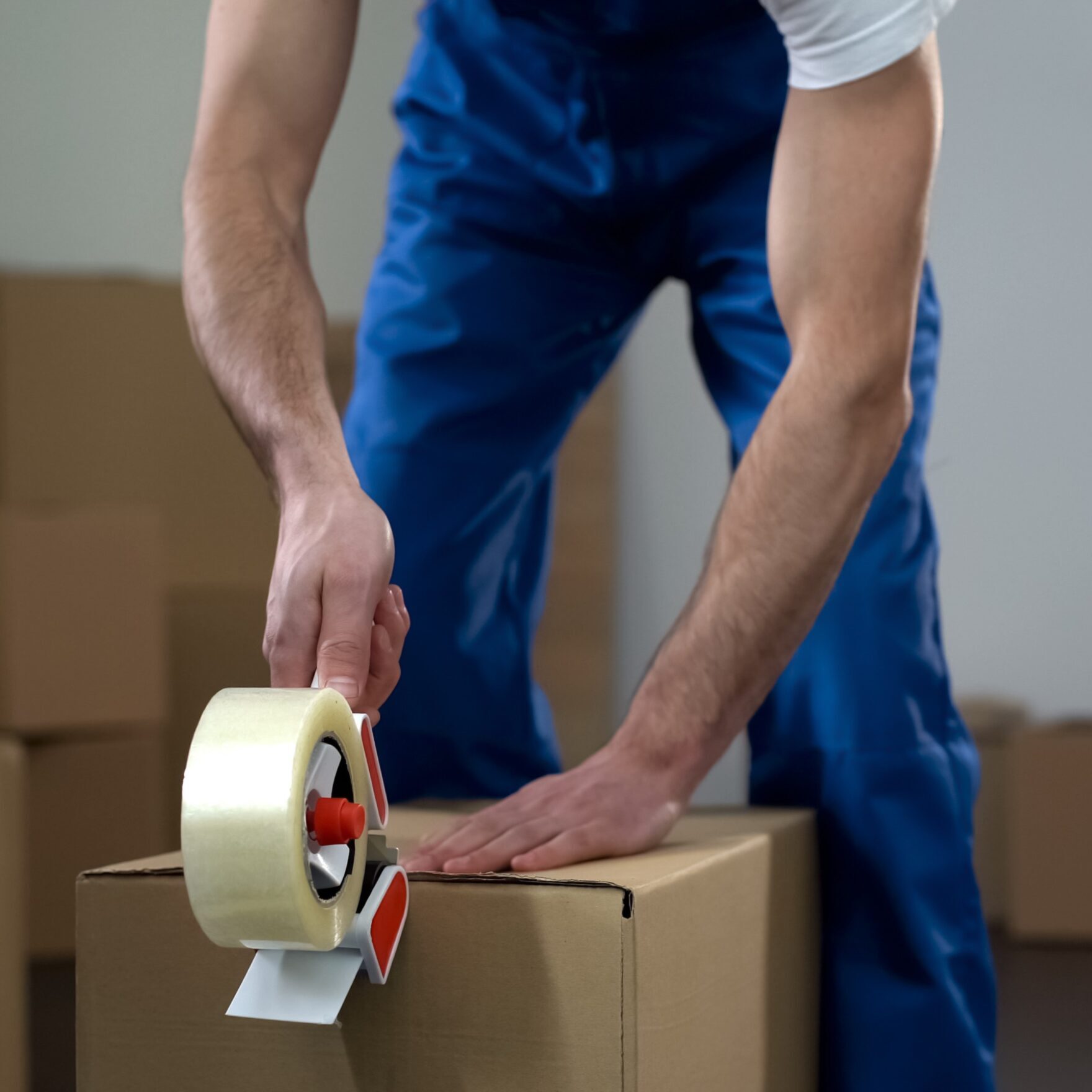 Person taping a cardboard box shut.