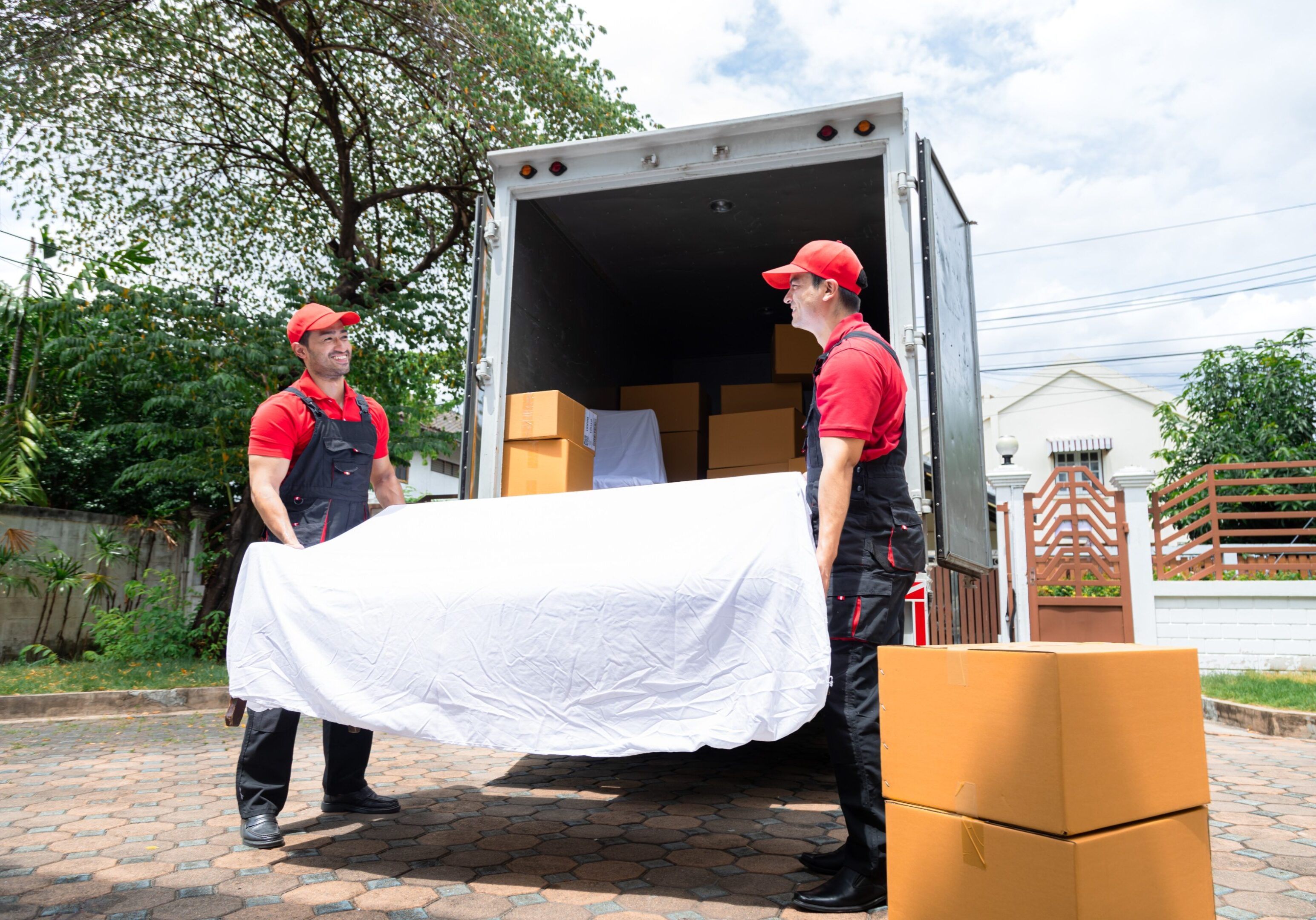 Movers carrying mattress near delivery truck.